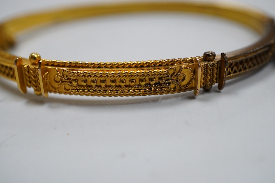 Two Victorian gold bangles, late 19th century, each of hinged design, with rope twist decoration, one later set with a carré-cut diamond, the other suspending a cross from a safety chain, inner circumferences approximate